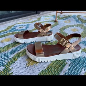 Metallic bronze, white-soled platform sandals.